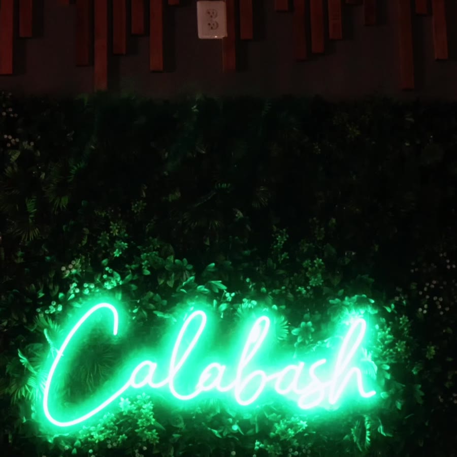 The green neon Calabash sign on the living wall